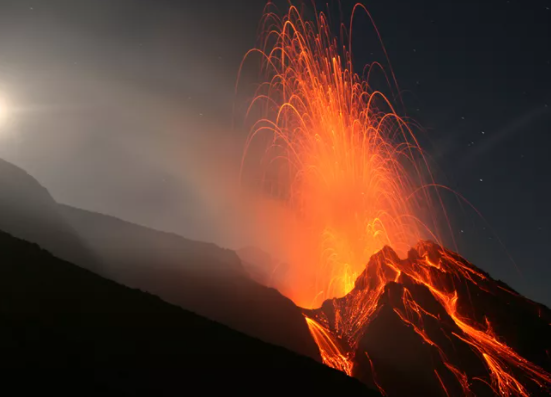 A volcano erupting at night Description automatically generated