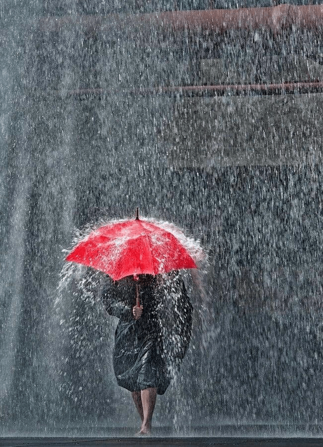 A person holding an umbrella in the rain Description automatically generated with medium confidence